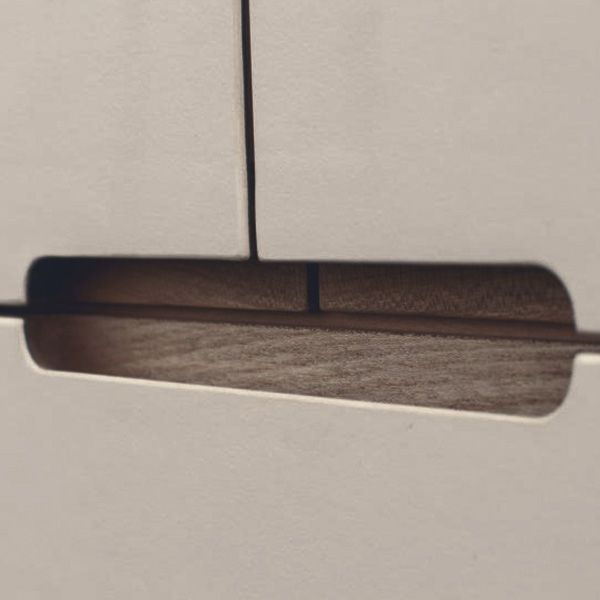 Detailaufnahme einer eingefrästen Griffmulde aus dunklem Holz an weißer Sideboard-Front