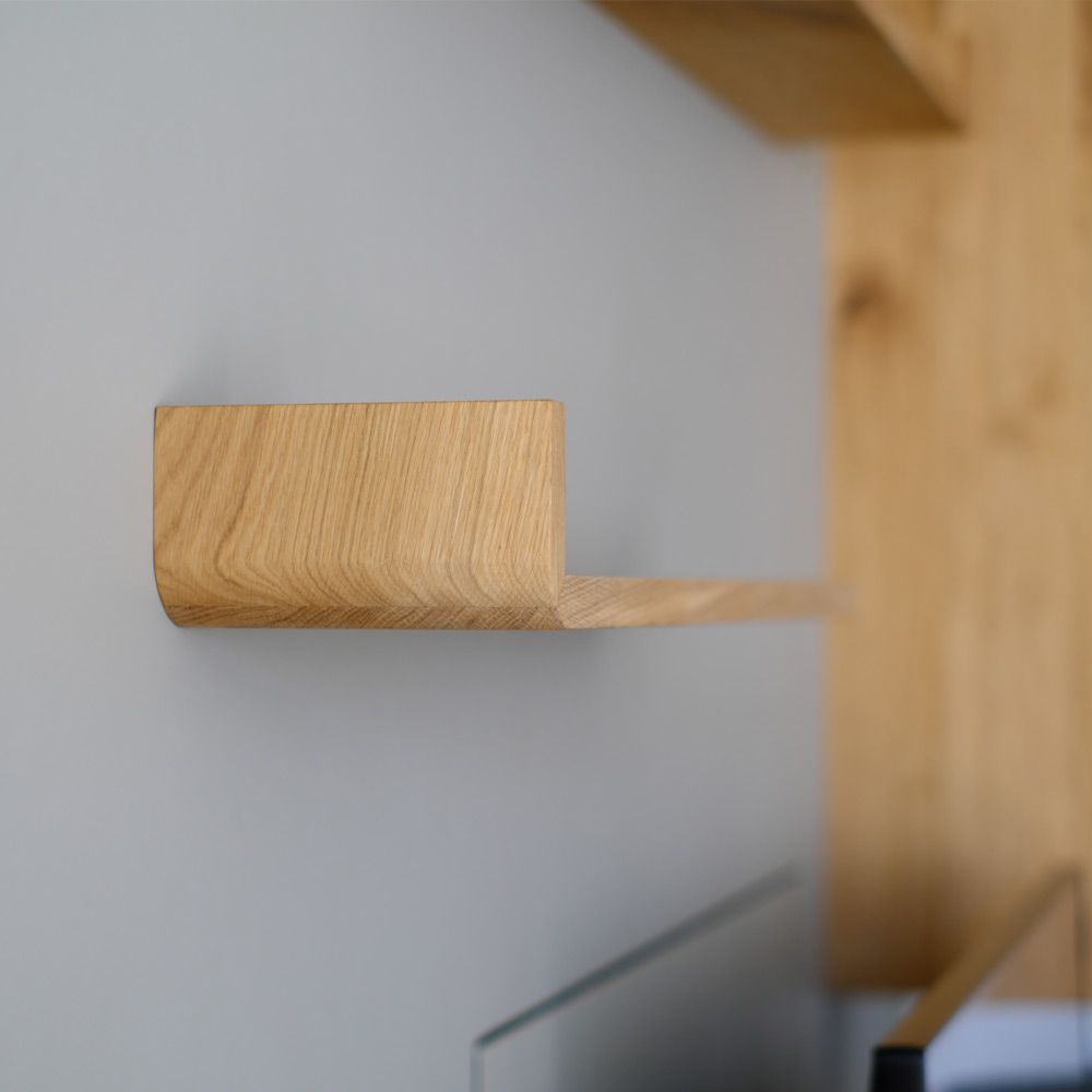 Detailaufnahme einer gerundeten Eiche-Massivholz-Ecke mit sichtbarer Maserung an der Wand