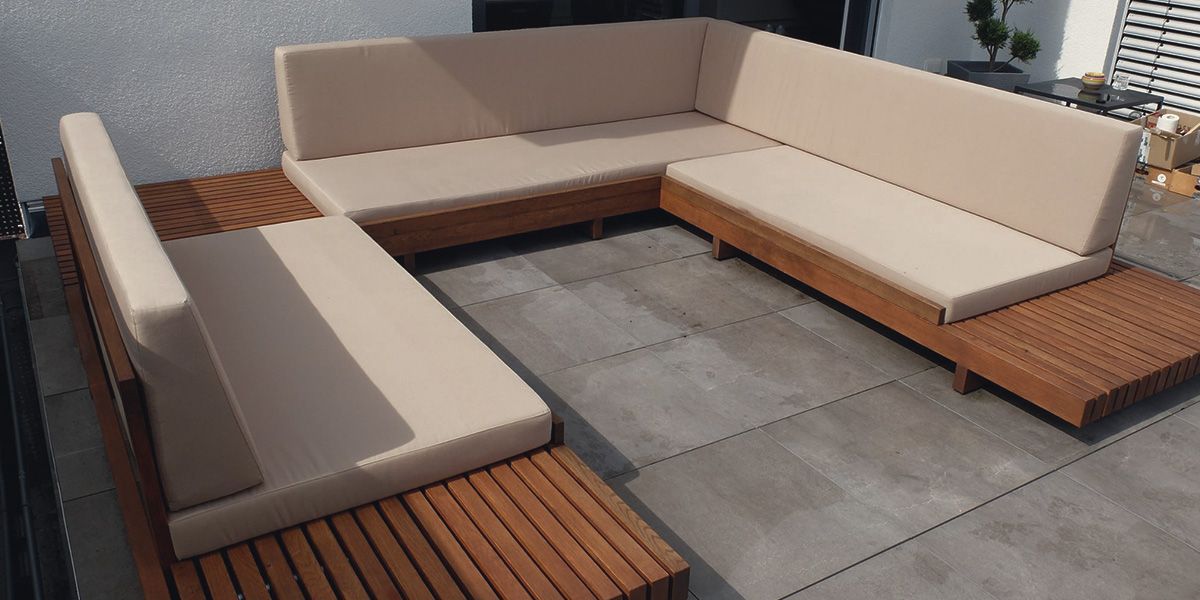 Terrassen-Loungemöbel aus Eiche mit beigen Polstern als U-förmige Sitzecke auf gefliester Terrasse