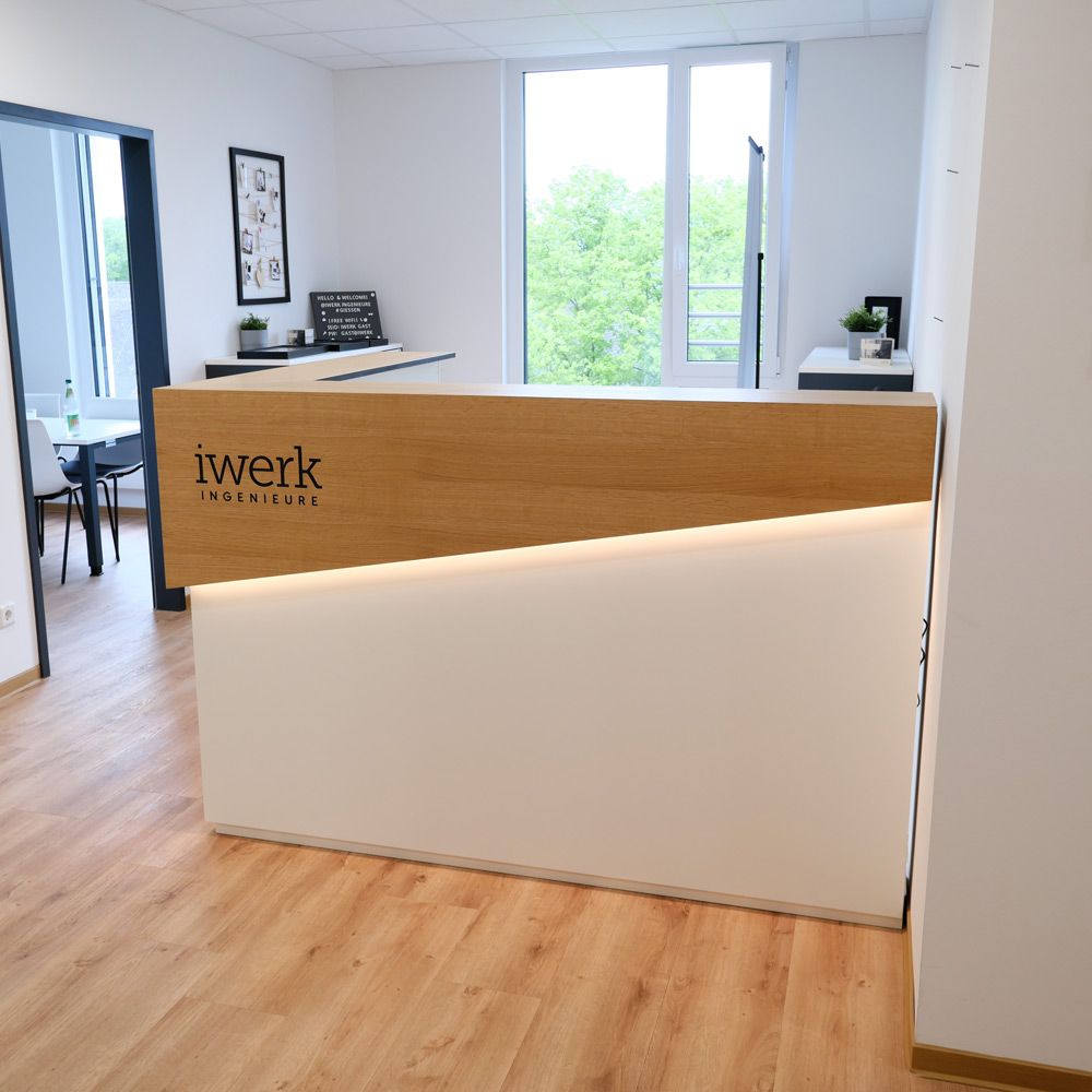 Empfangstheke aus Eiche und weißem Lack mit LED-Lichtkante, Logo und Blick ins Büro
