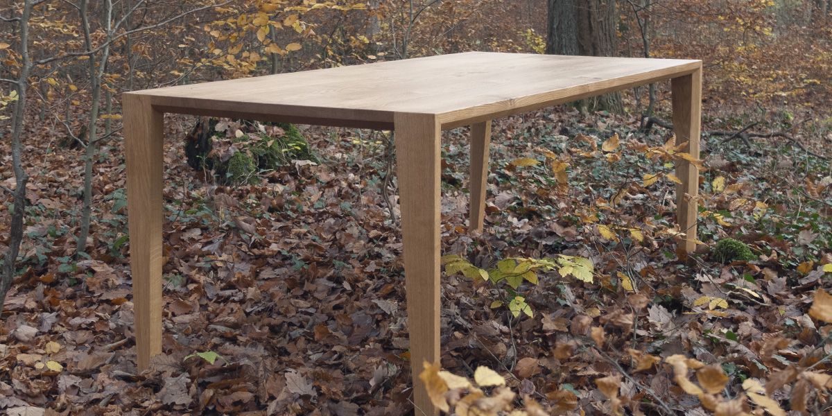 Massivholztisch mit schmalen Beinen aus diagonaler Ansicht im Herbstwald