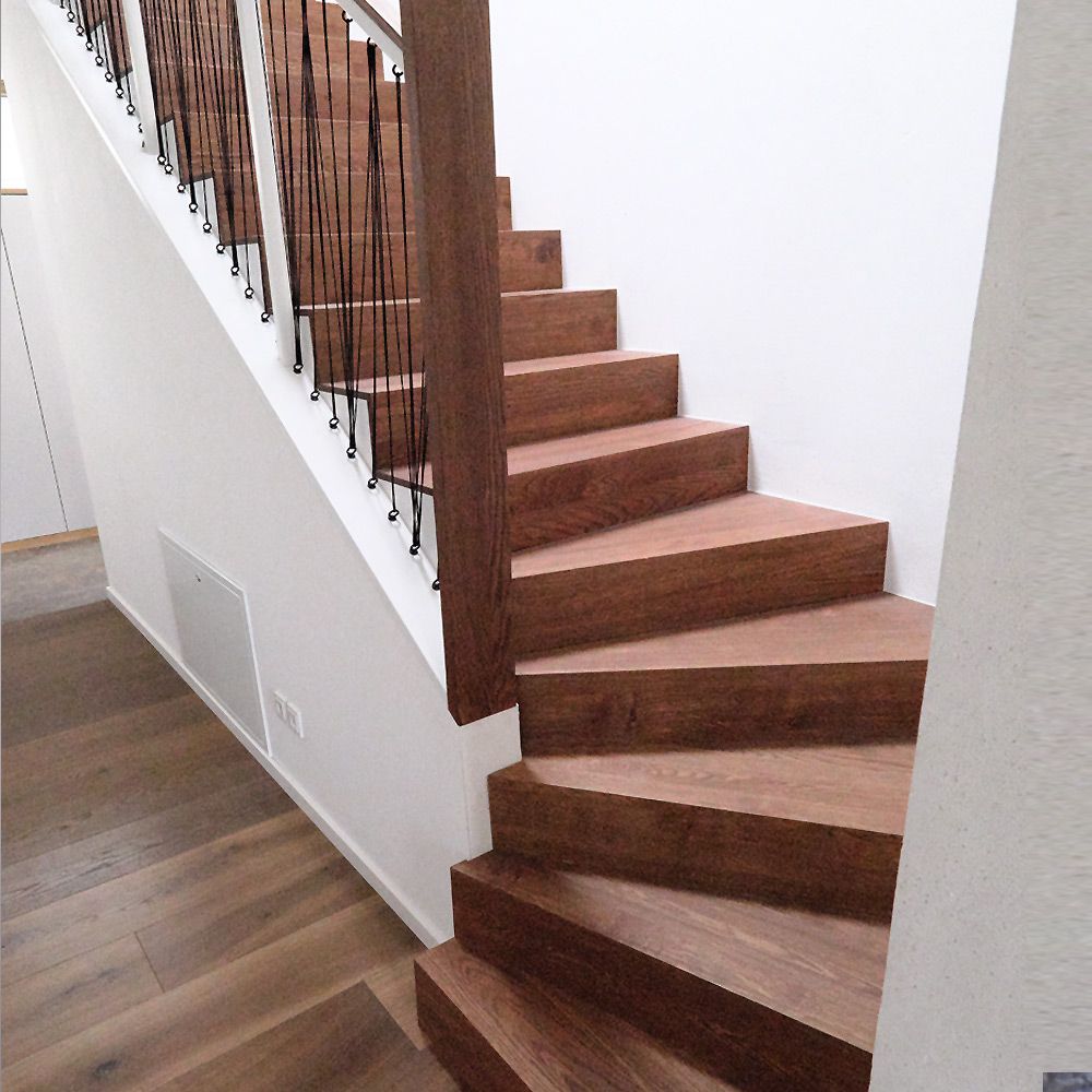 Gewendelte Treppe aus dunkler Eiche mit Brüstungsgeländer aus Schnurspannung in weißem Treppenhaus