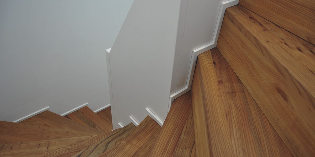 Massivholztreppe mit gewendelten Stufen und weiß lackierter Wangenverkleidung im Detail