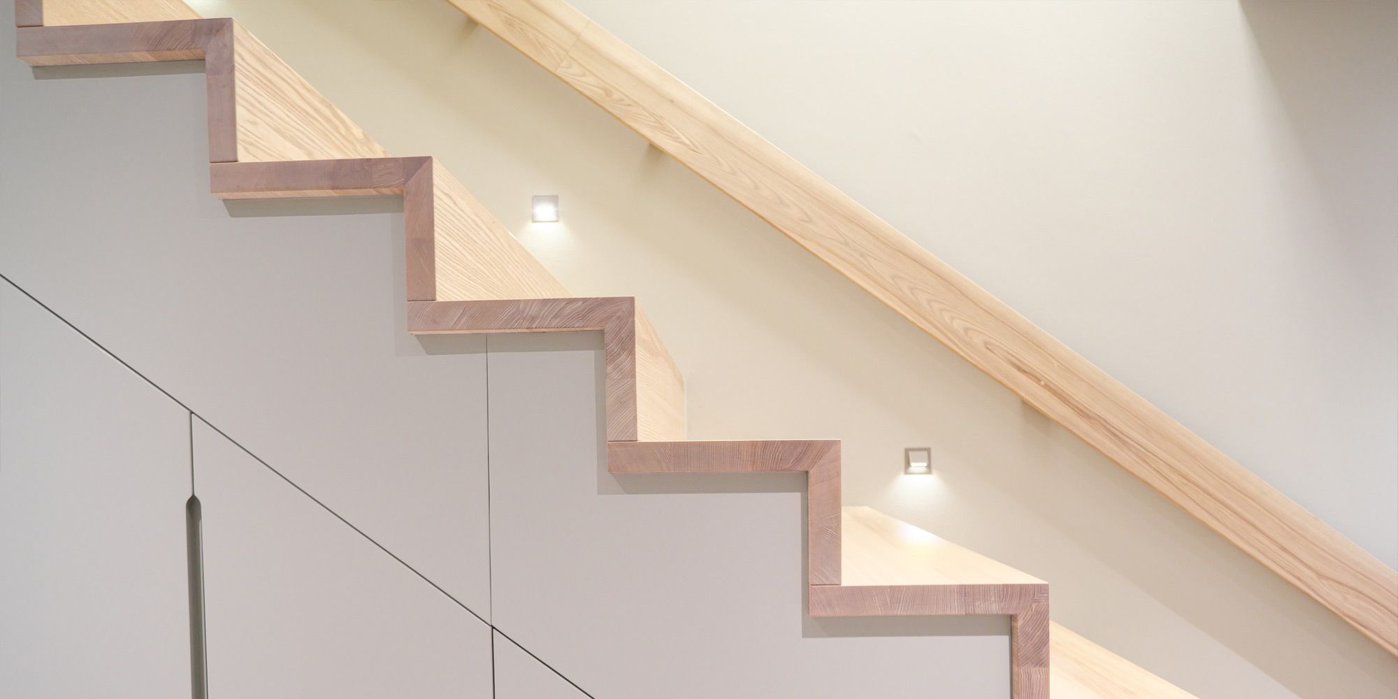 Treppe mit massiven Eschenholz-Stufenkanten und integriertem Stauraumschrank unter den Stufen