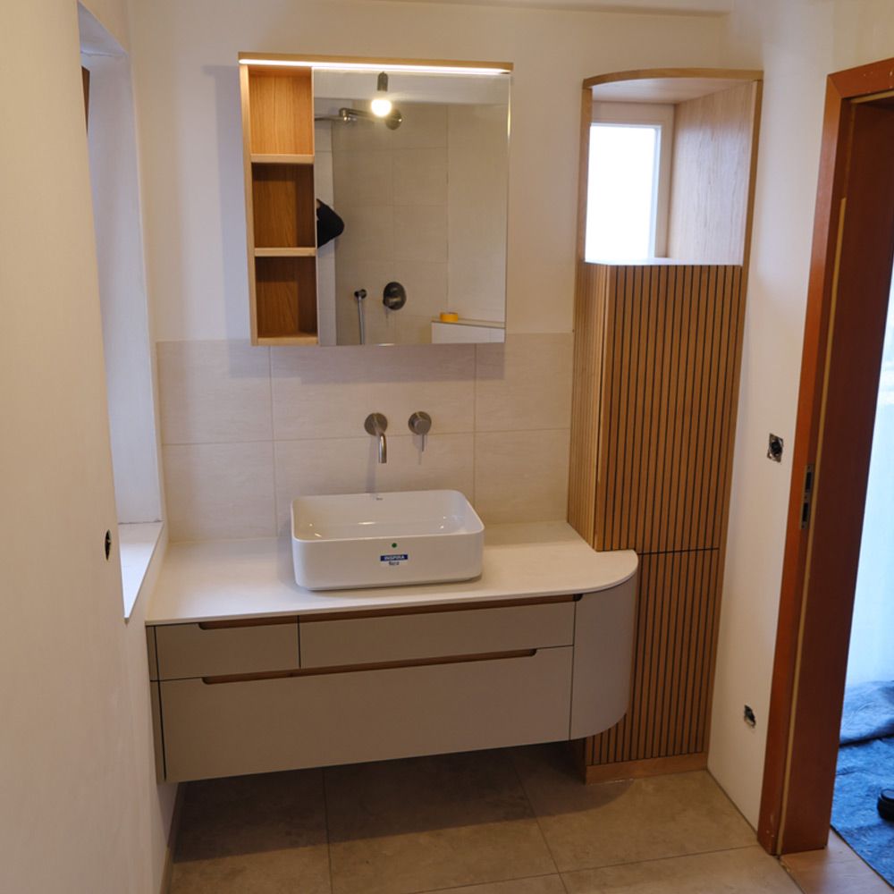Badezimmer mit Waschtisch in Linoleum und Eiche, gerundetem Lamellenschrank und beleuchtetem Spiegelschrank