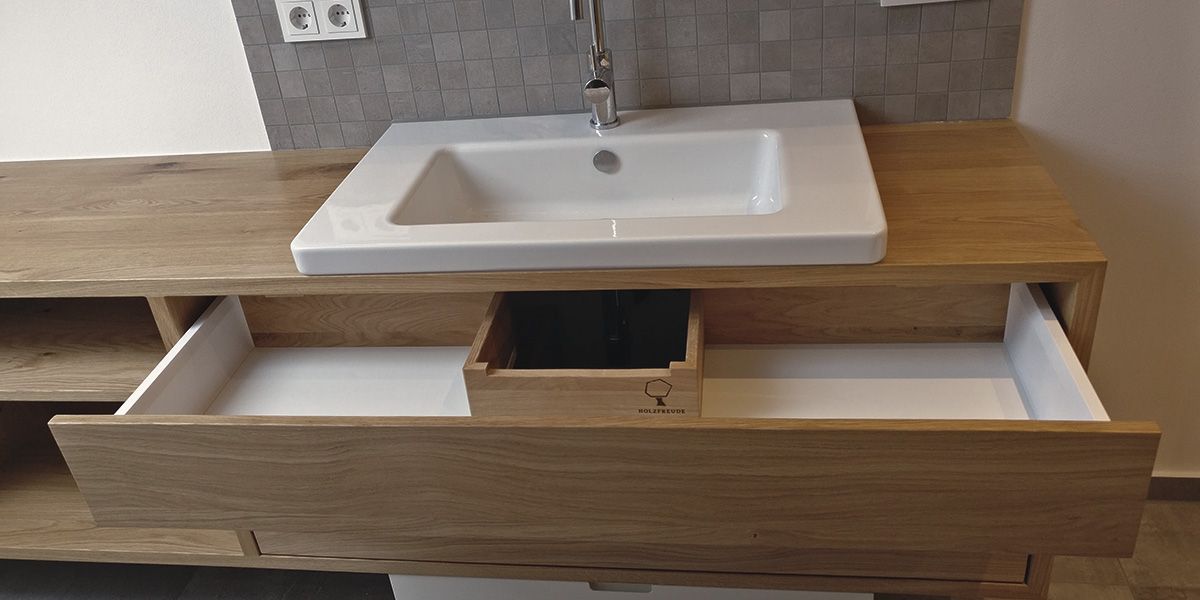 Geöffnete Schublade eines Eiche-Waschtischs mit Holzfreude-Branding, Einbauwaschbecken und Chromarmatur