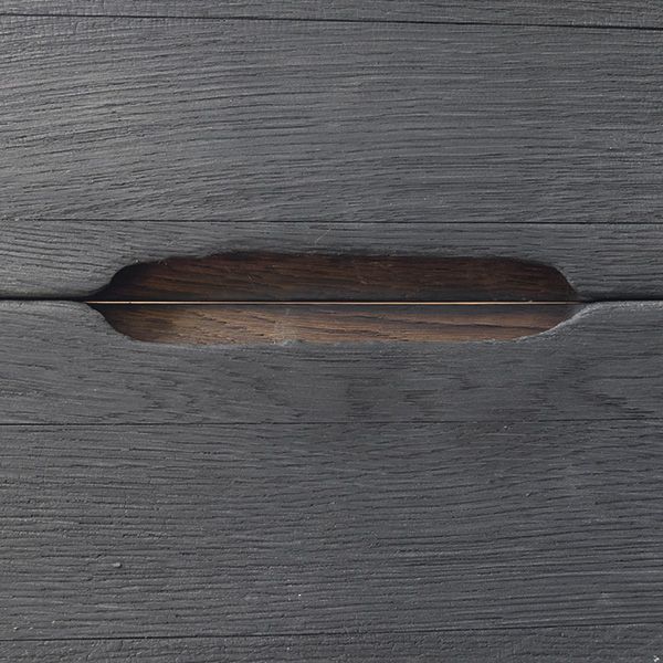 Detail einer eingefrästen Griffmulde in schwarz lasierter Holzfront mit sichtbarer Maserung