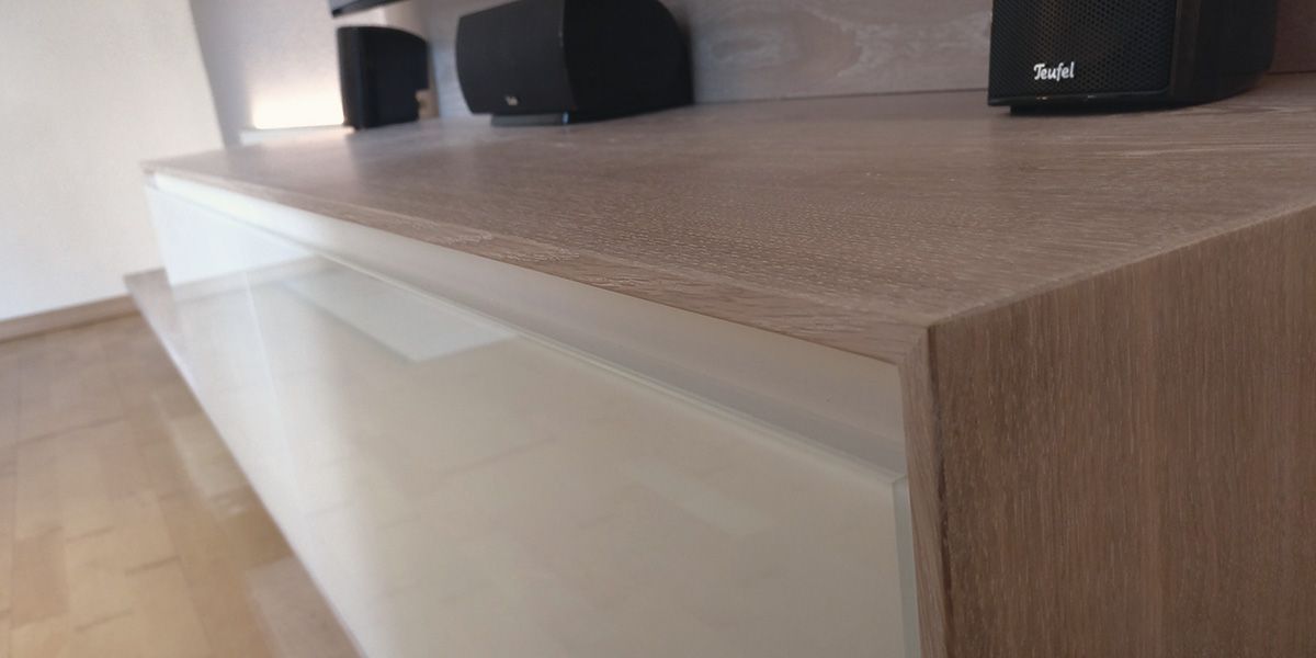 Detailaufnahme TV-Sideboard mit Holzmaserung und weißer Hochglanzfront