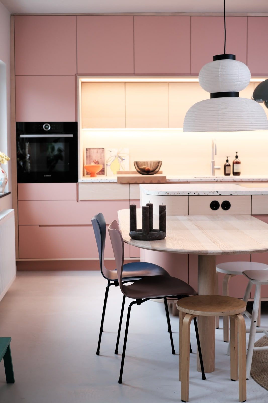 Küche mit rosa Fronten, Papierlampenschirm und gemütlichem Essbereich mit Stühlen
