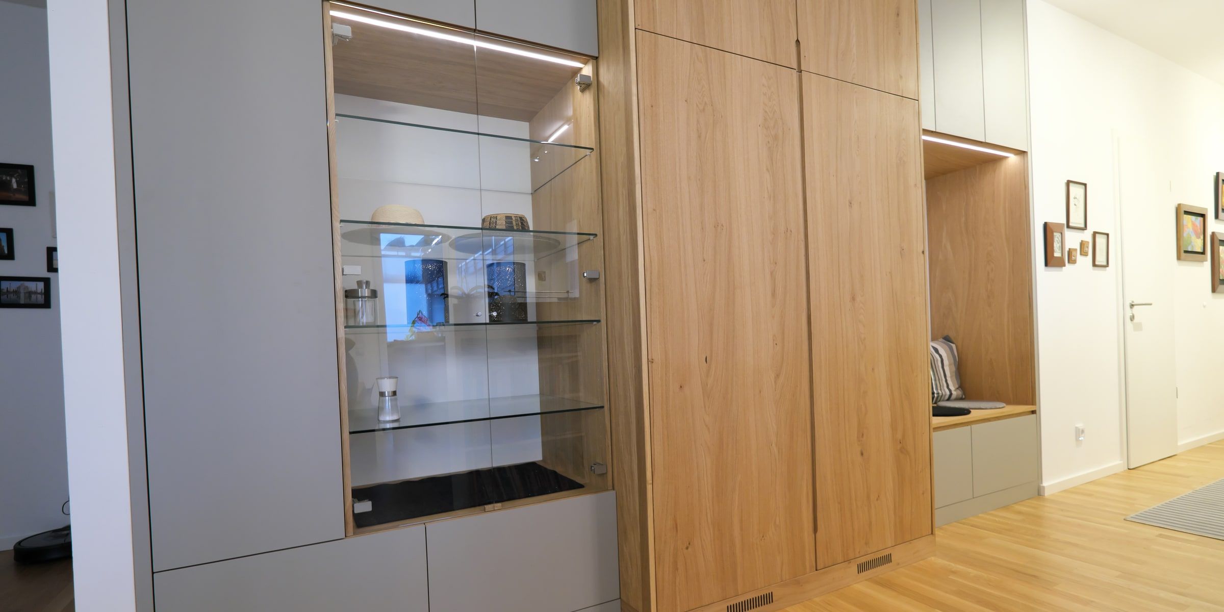 Maßgefertigte Garderobe aus Eiche mit Glasvitrine und Sitzbanknische im hellen Flur