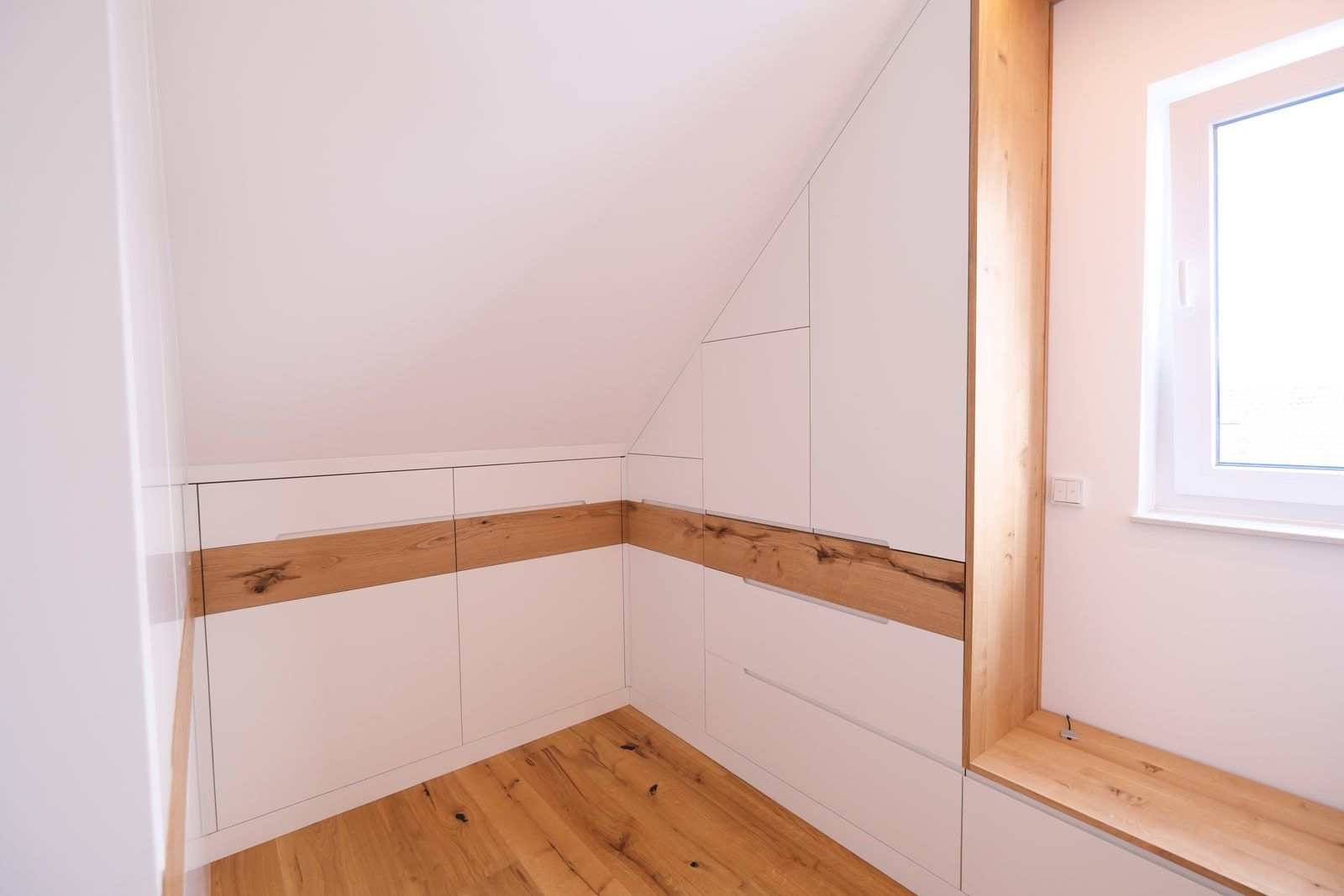 Weißer Dachschrägenschrank mit markanter Astholz-Griffleiste aus Eiche massiv