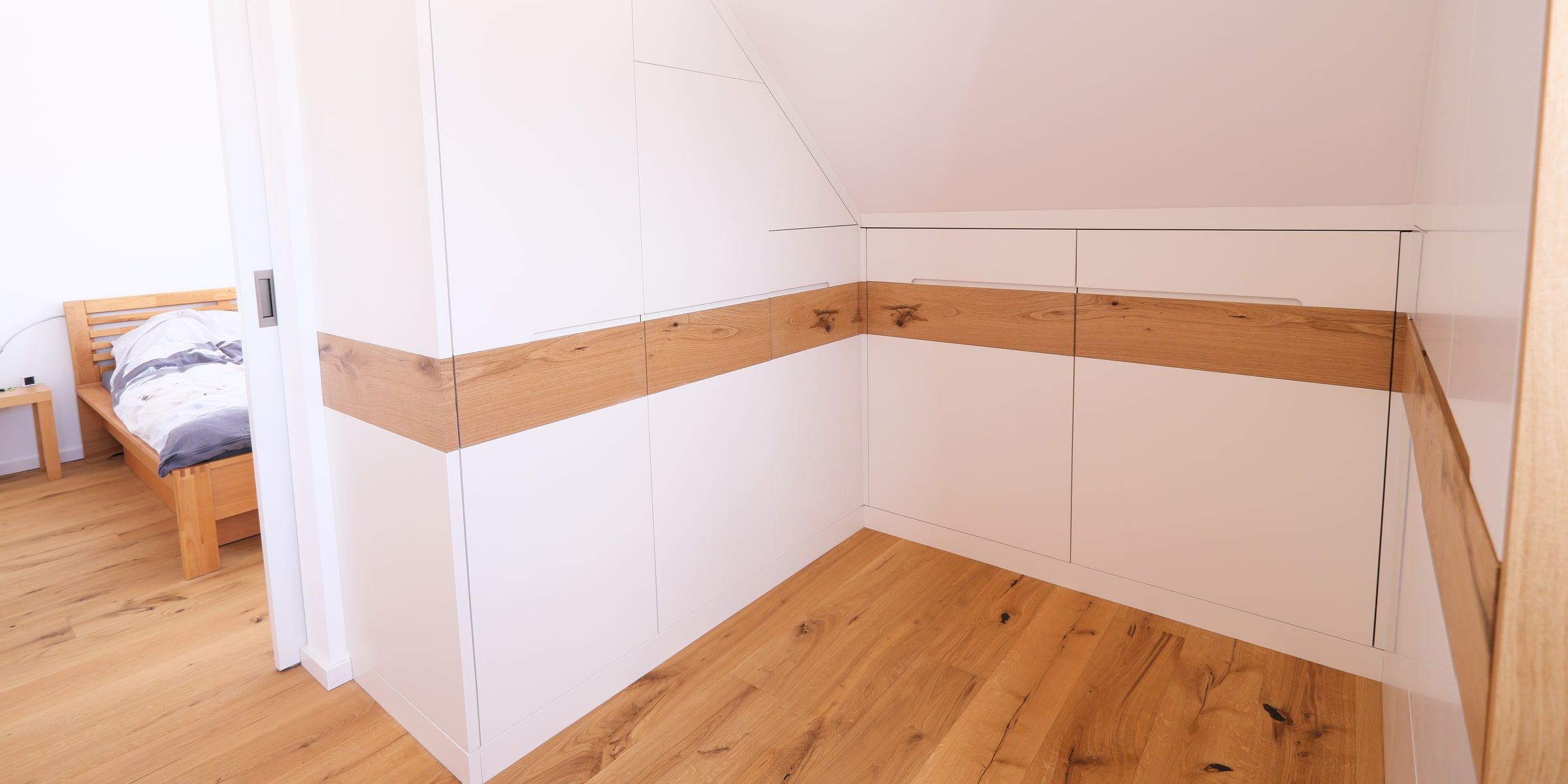 Weißer Dachschrägenschrank mit Griffleiste aus Eiche massiv im Schlafzimmer