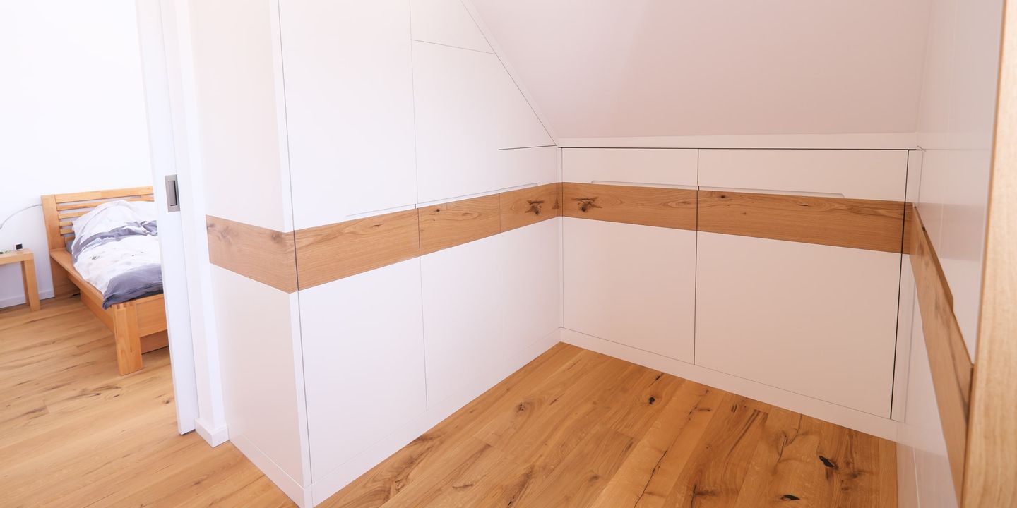 Weißer Dachschrägenschrank mit Griffleiste aus Eiche massiv im Schlafzimmer