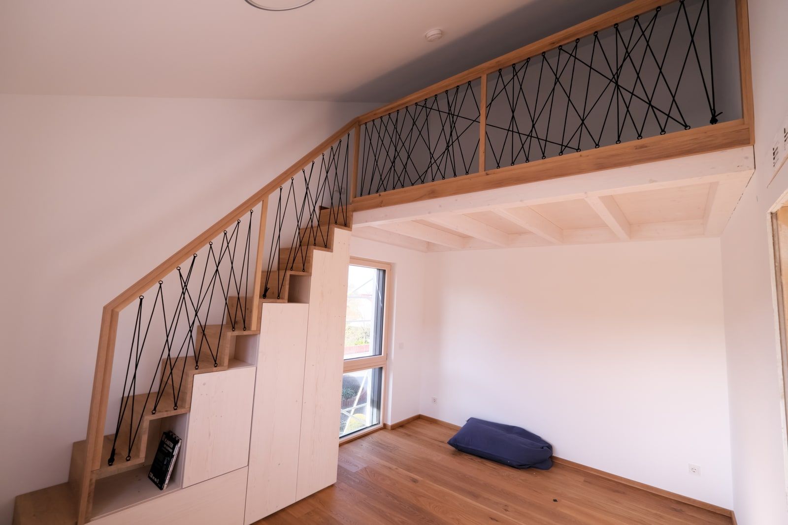 Offene Galerie mit Massivholztreppe und Rautenseilgeländer über zwei Ebenen