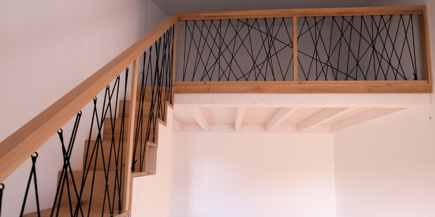 Holztreppe mit Empore und Seilgeländer, Blick auf Dielenboden im Dachgeschoss