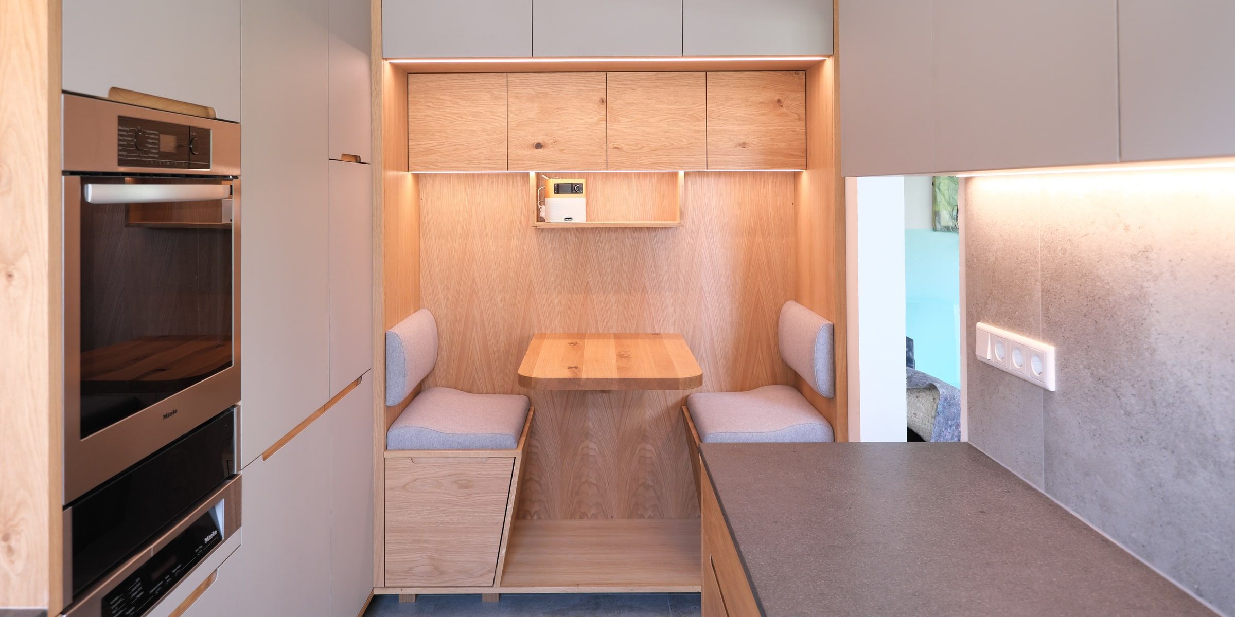 Küche mit Sitzecke aus Massivholz Eiche, Polsterbank und warmer LED-Beleuchtung