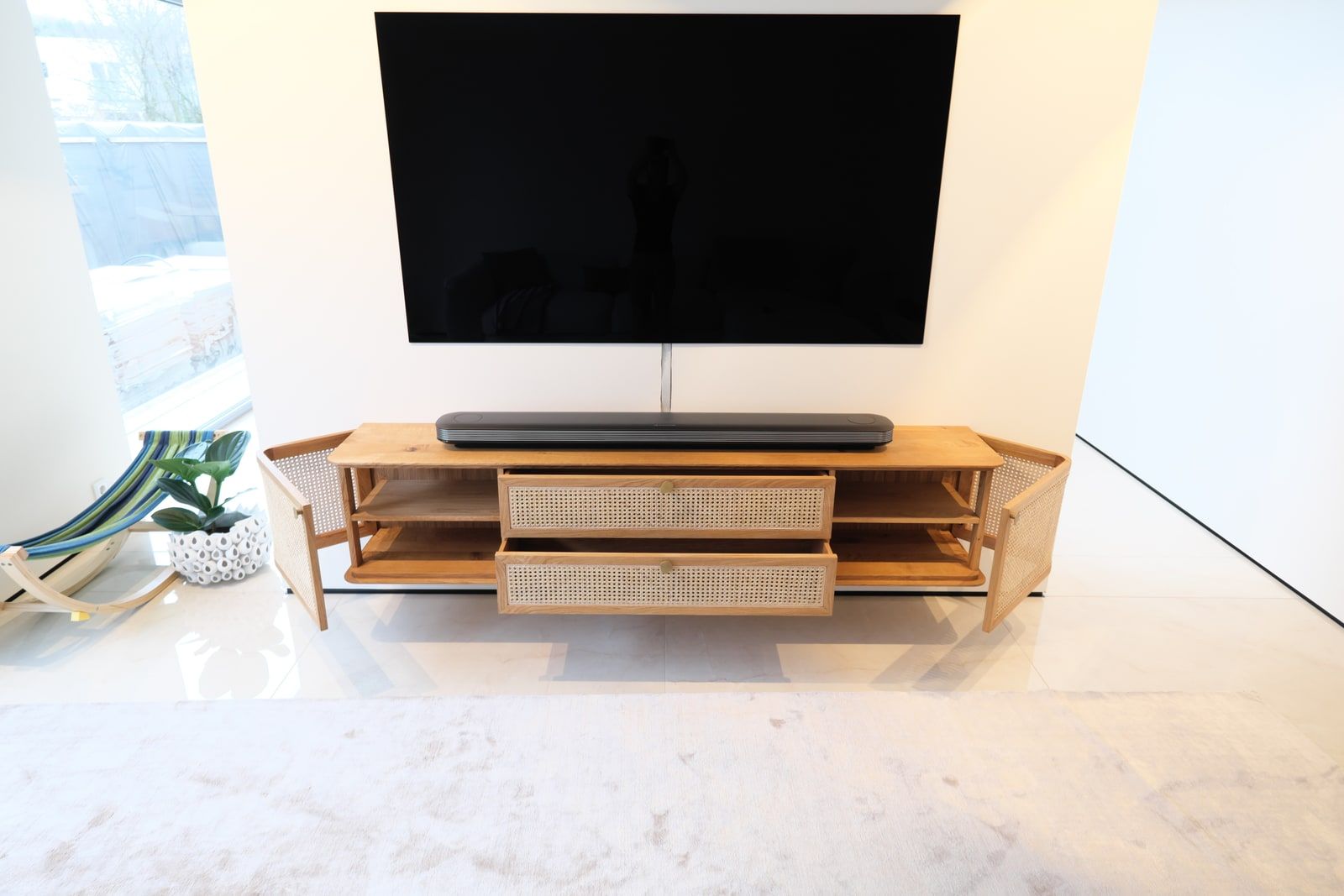 Eiche-Sideboard mit Wiener Geflecht und geöffneten Fronten im hellen Wohnzimmer mit Terrassenblick