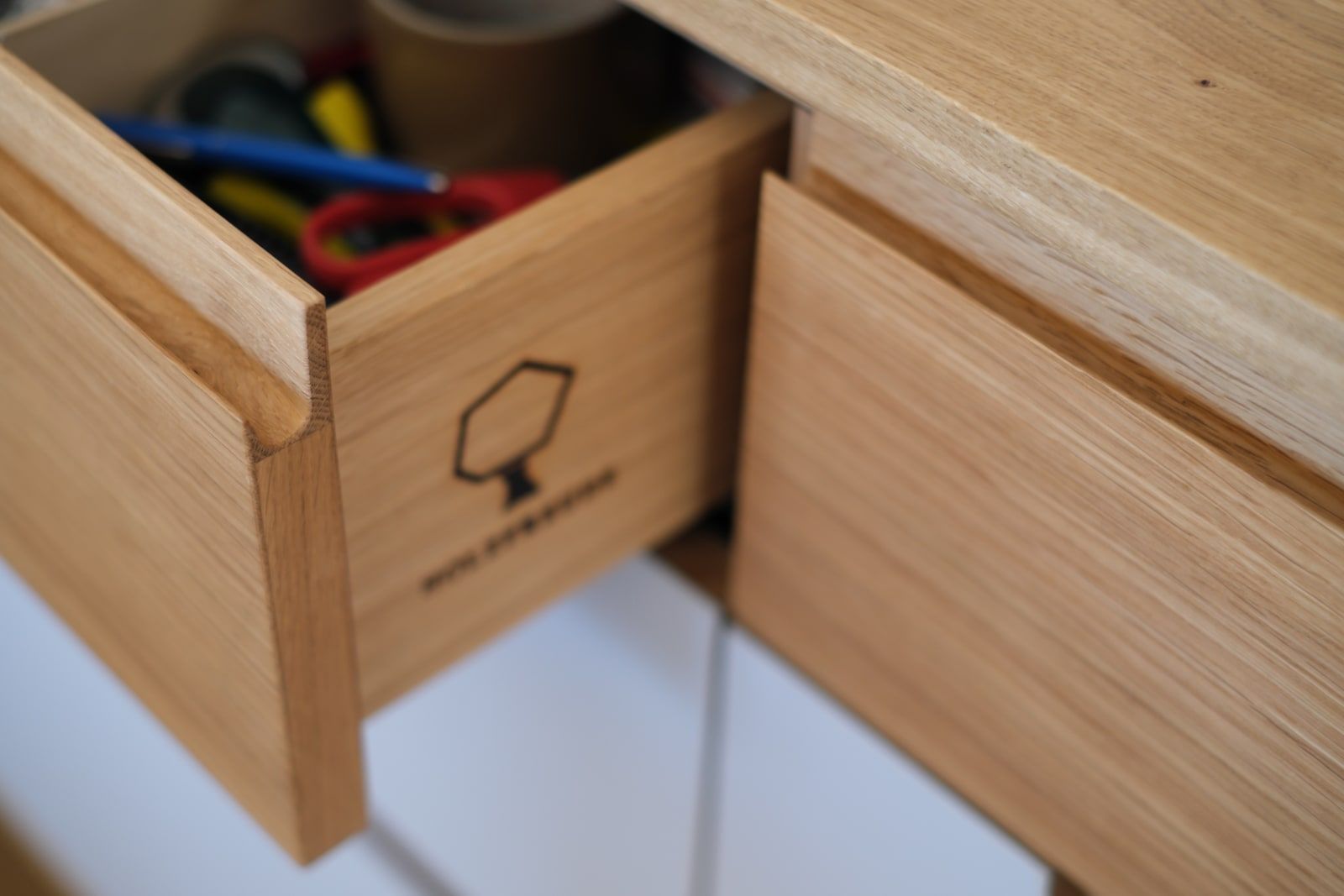 Offene Massivholzschublade mit eingebranntem Holzfreude-Logo, Handwerksdetail aus Eiche