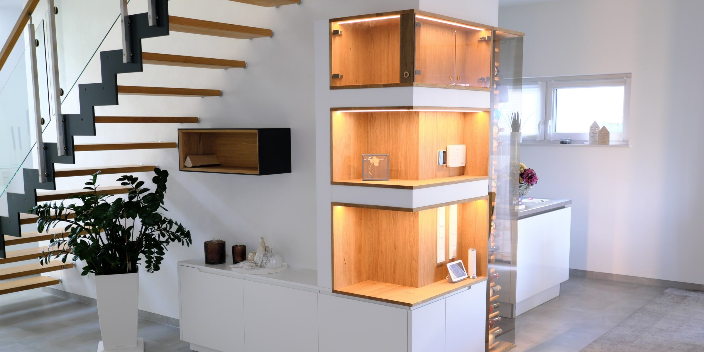 Weinregal aus Eiche als Raumteiler neben offener Treppe im Wohnzimmer