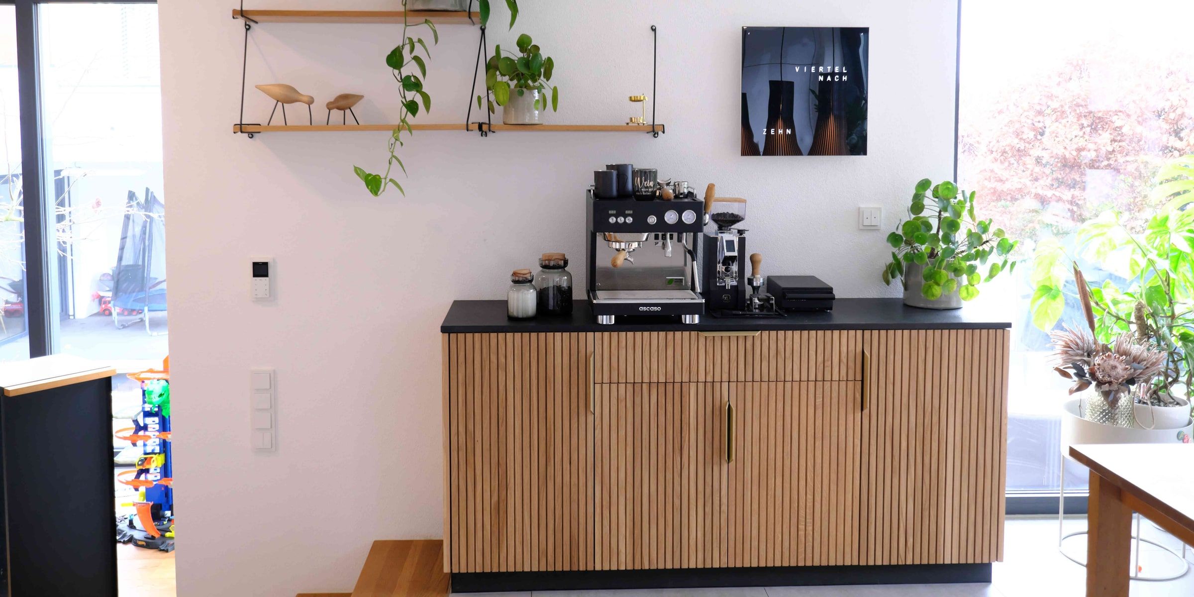 Helles Wohnzimmer mit Coffeepoint-Sideboard aus Eiche massiv vor großer Fensterfront