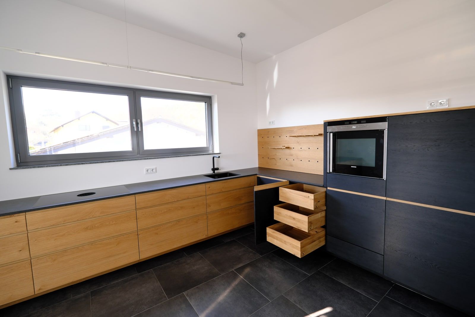 Offene Massivholzküche mit Fenster, Eiche-Fronten und anthrazitfarbener Schrankwand