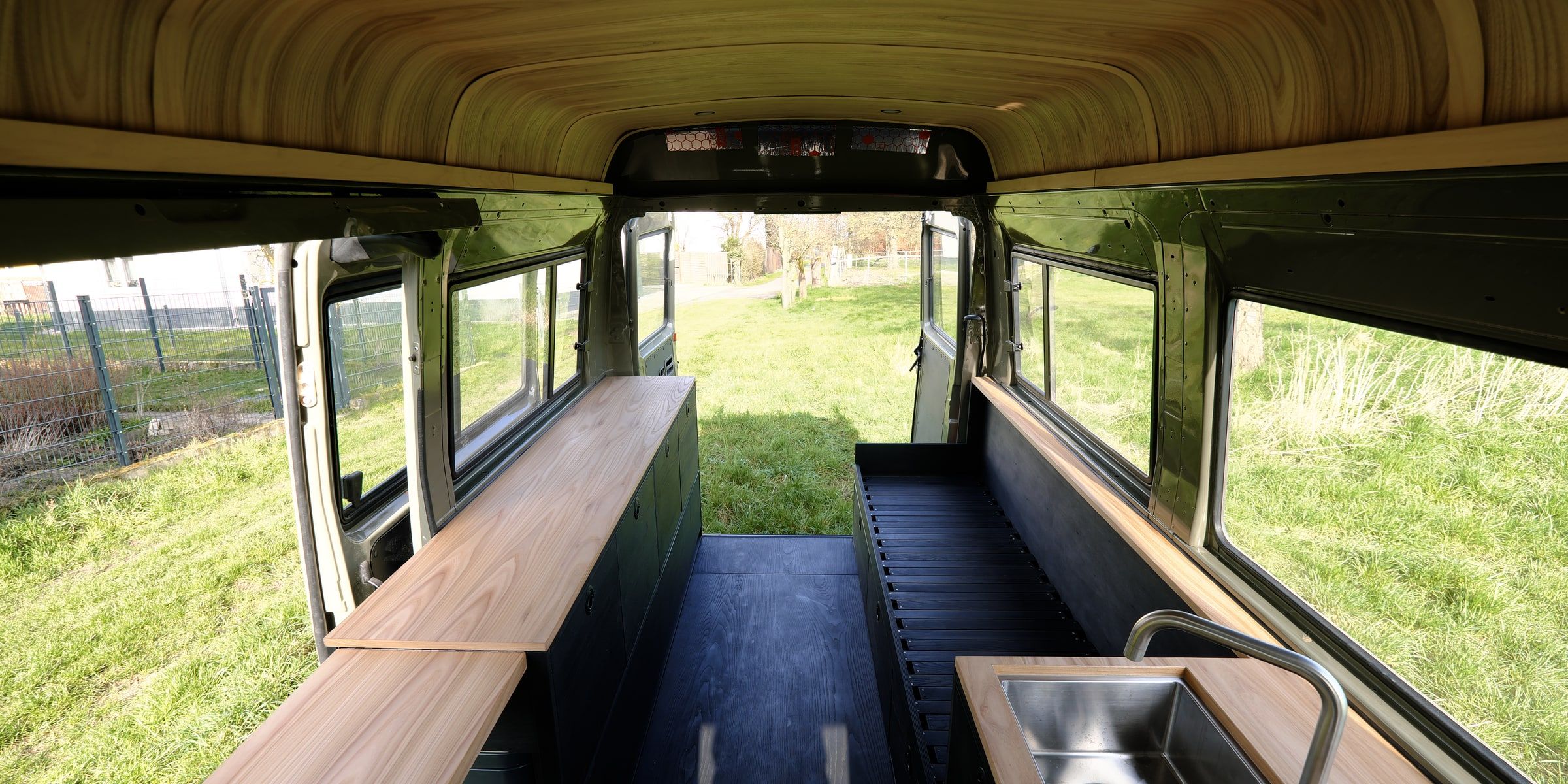 Campervan mit geschwungener Holzdecke, Massivholz-Arbeitsplatten und Küchenzeile