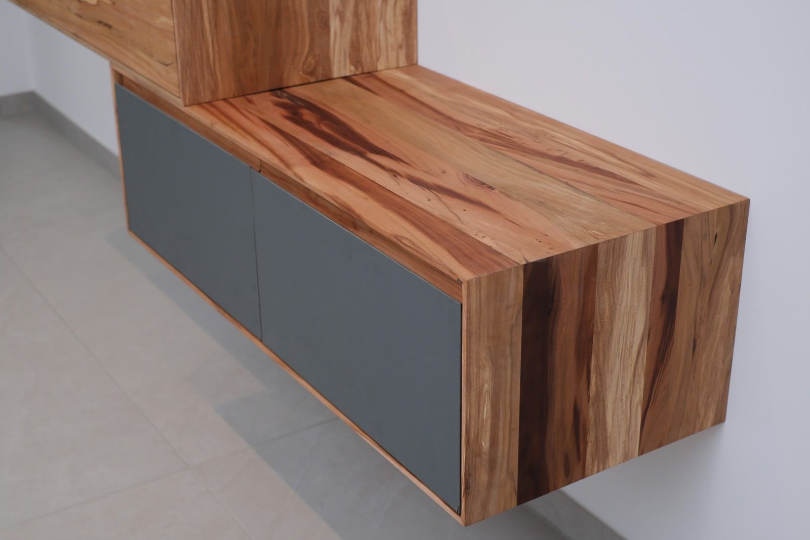 Nahaufnahme der Holzmaserung und grauen Front eines modernen Massivholz-Sideboards