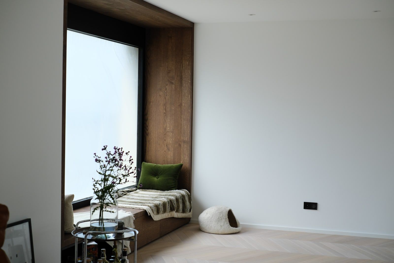 Holz-Sitzbank in Fensternische mit weiter Wandfläche und Parkettboden