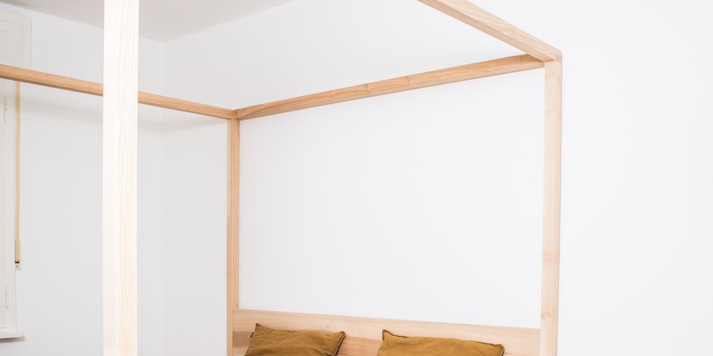 Himmelbett aus massiver Esche mit senffarbenen Kissen im hellen Schlafzimmer