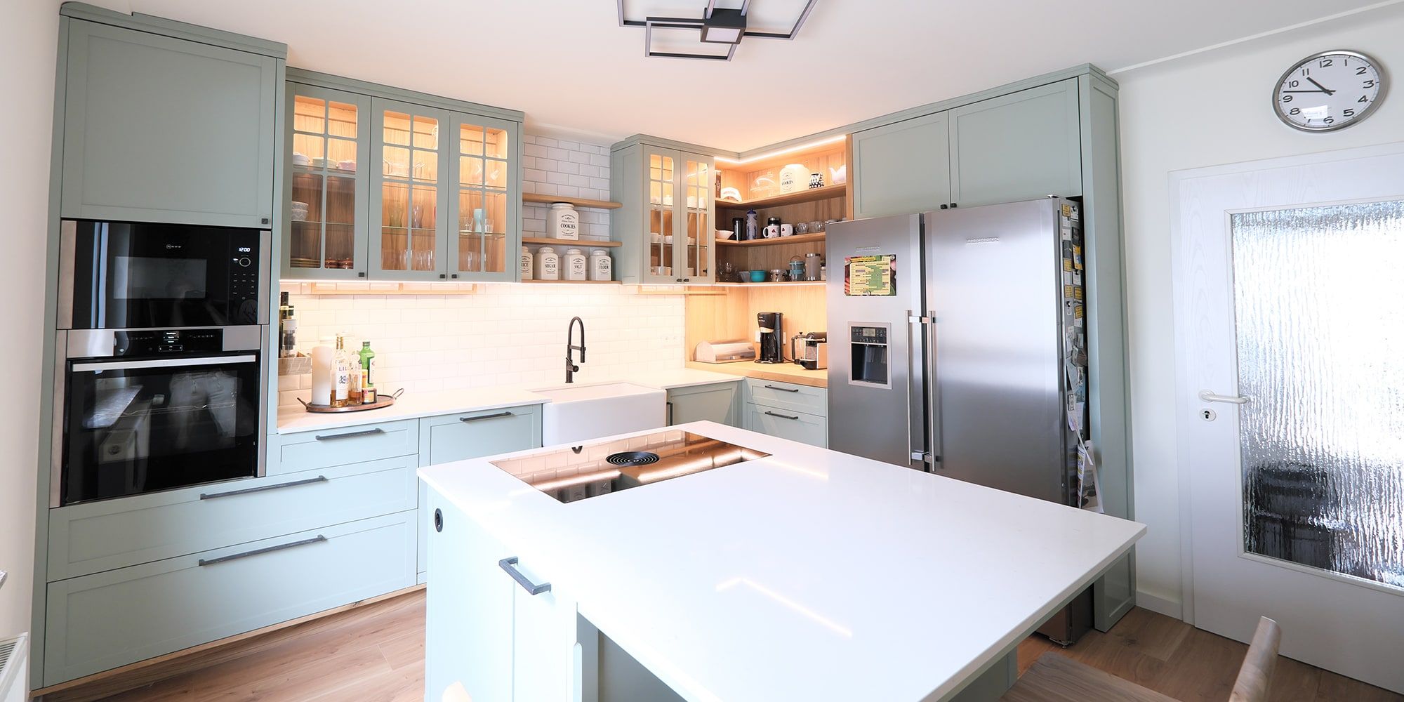 Landhausküche in Salbeigrün mit Kücheninsel, Edelstahlkühlschrank und Sprossenglasfronten