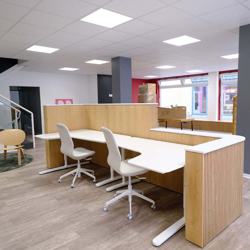 Maßgefertigter Arbeitsplatz mit Holztheke, Lamellenverkleidung und weißen Tischplatten im Büro